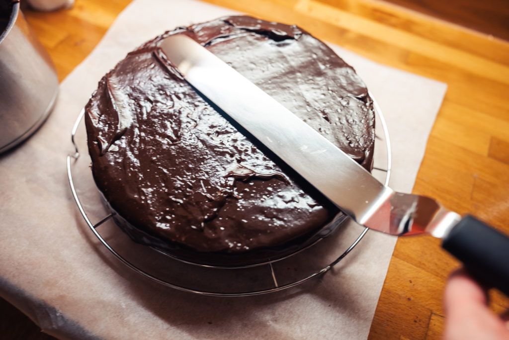 adding chocolate glaze to cloudberry sachertorte