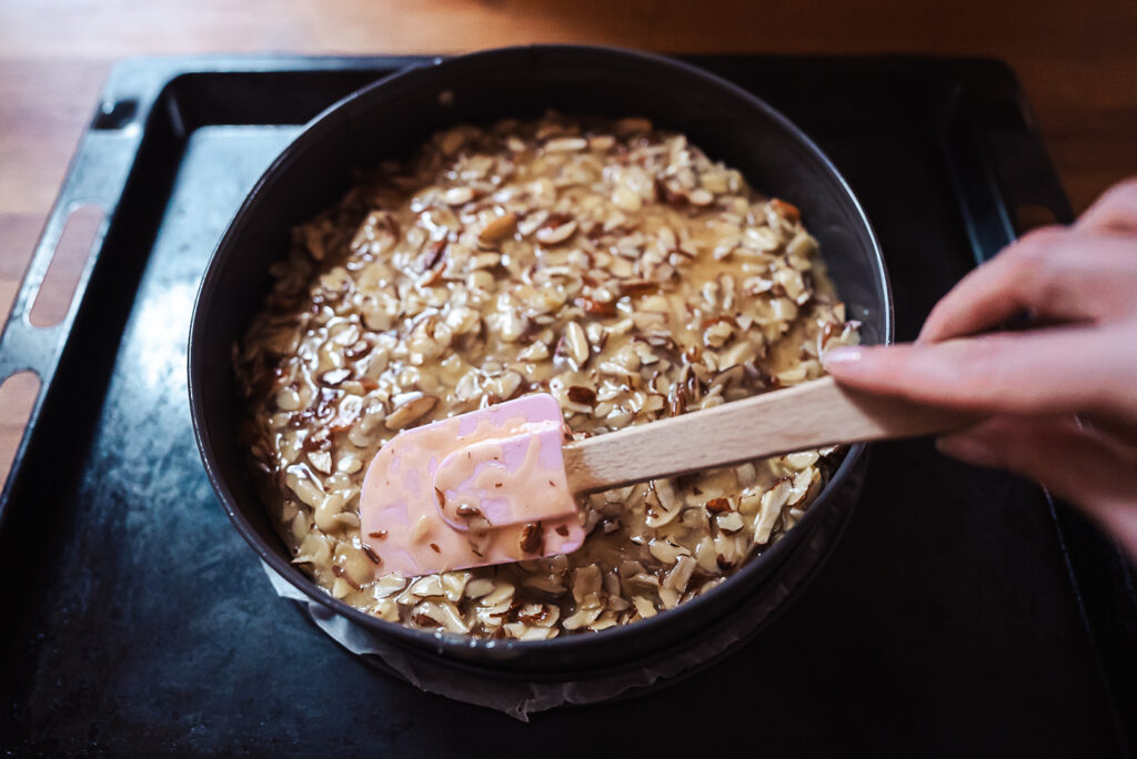 spreading almond topping on tosca cake