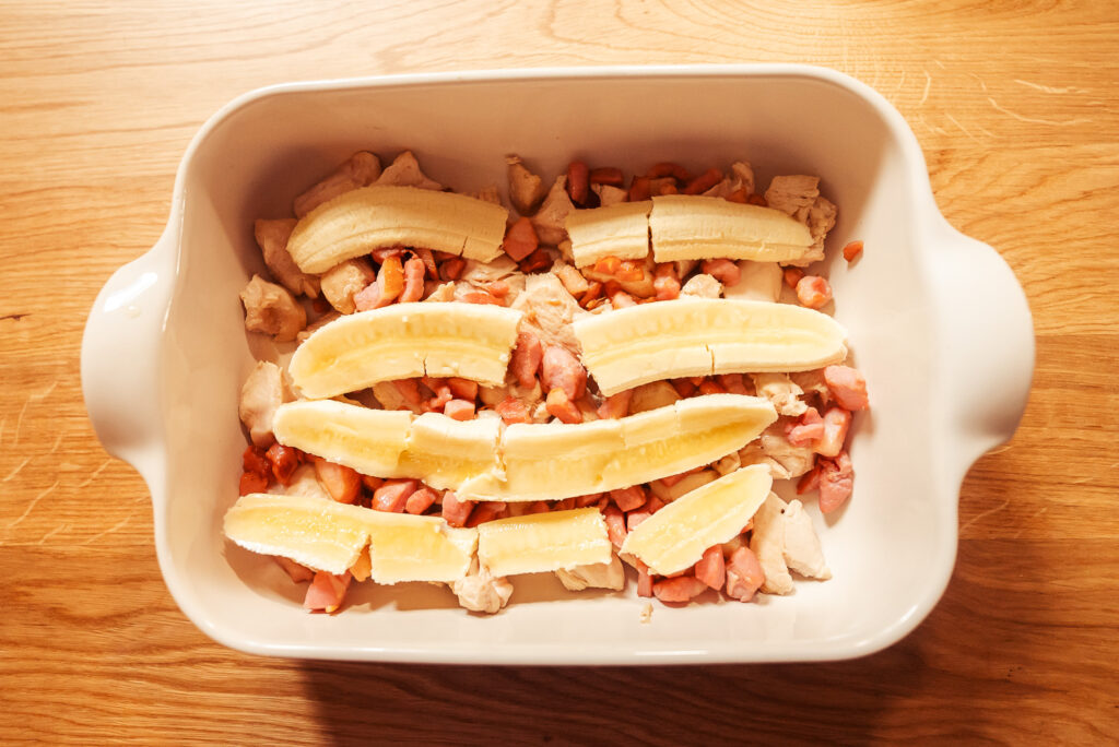 flying jacob casserole with chicken and bacon on the bottom and topped with slices of banana