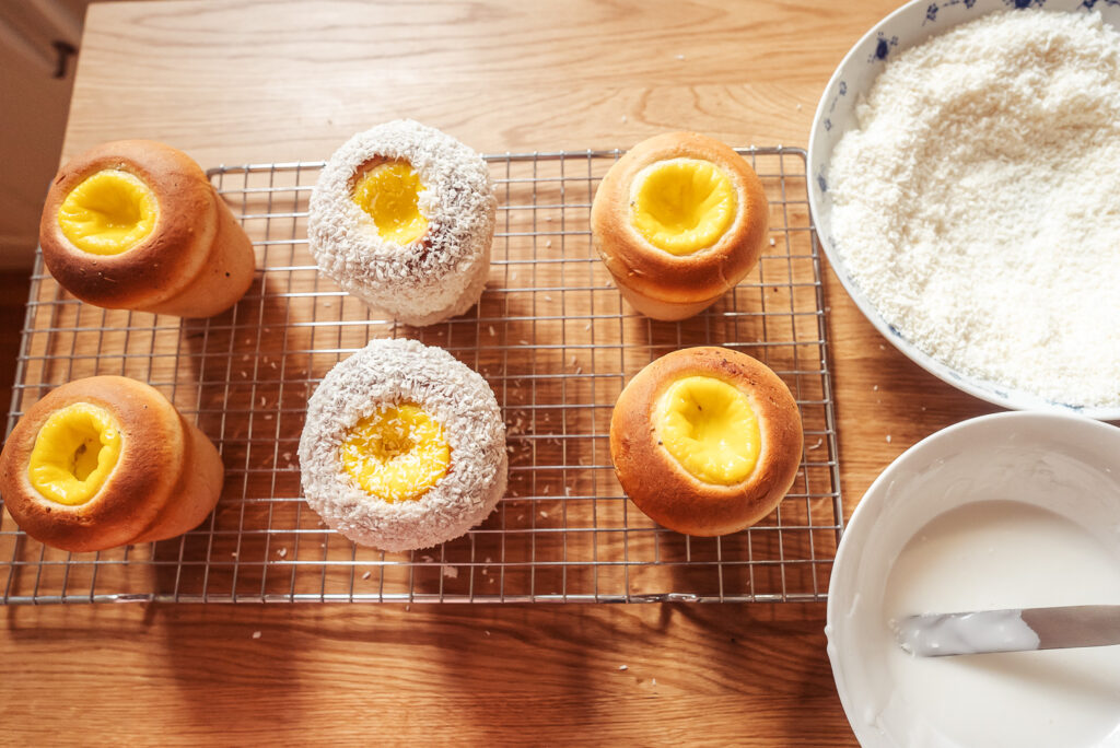 Decorating skoleboller on a wire rack with icing and coconut