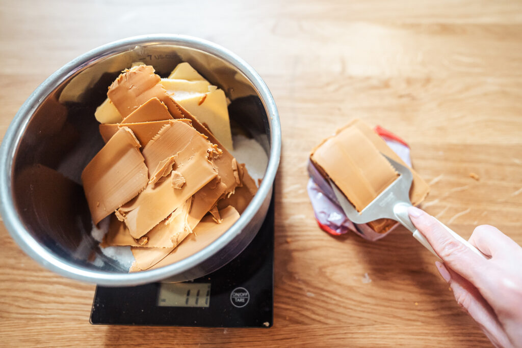 slicing Norwegian brunost, or brown cheese, and adding it to a saucepan with butter and sugar