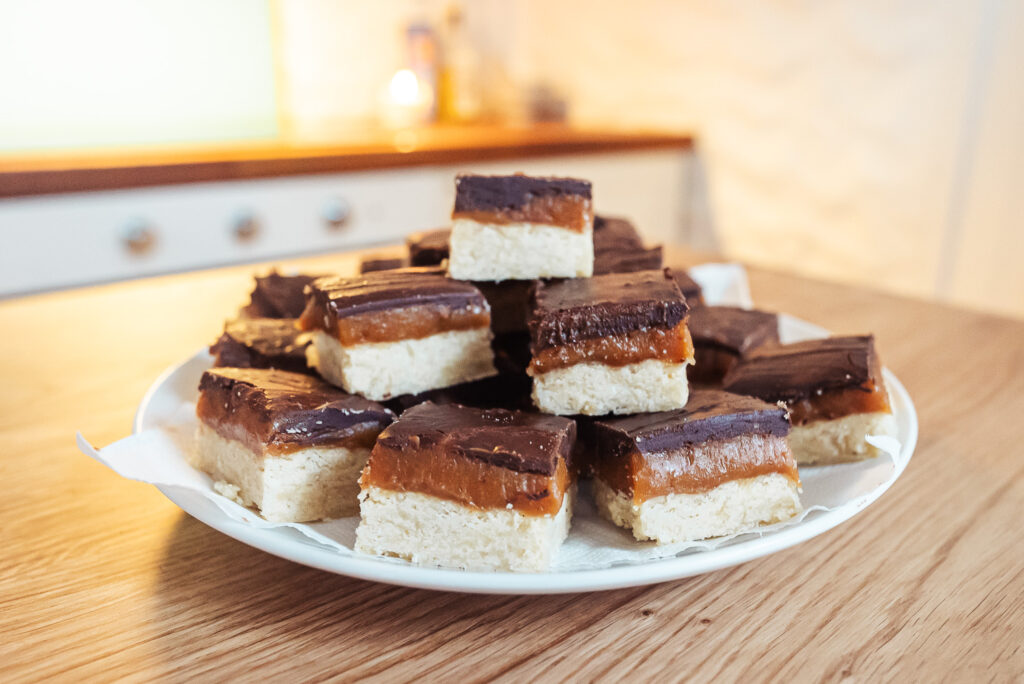 Norwegian brown cheese caramel squares stacked on a plate on a counter