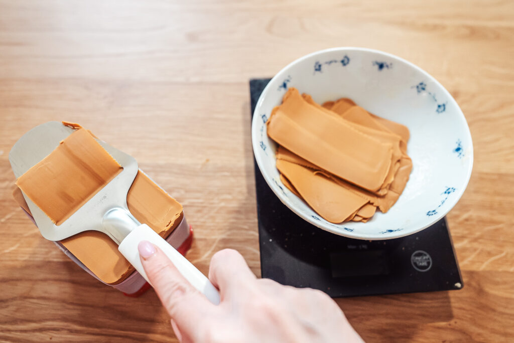 slicing brunost, norwegian brown cheese and putting it in a bowl