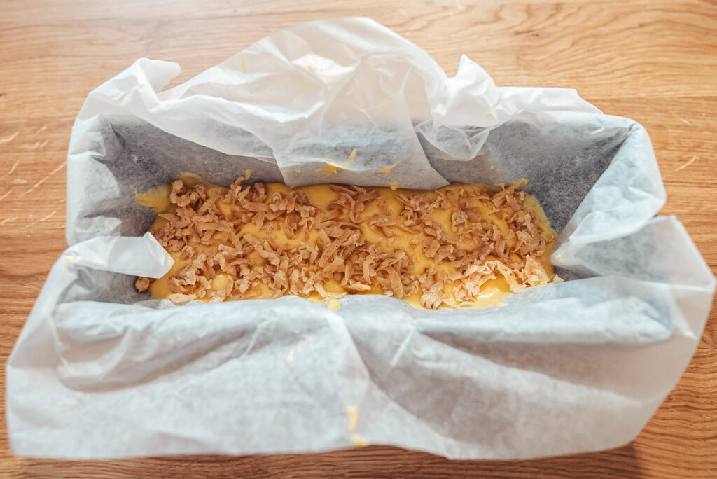 adding almond paste to apple cake dough in a loaf pan