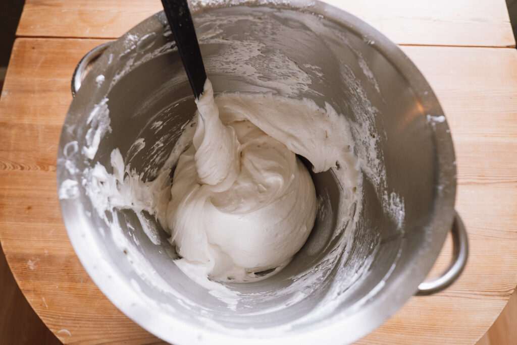 whipping meringue sponge cake batter in a mixing bowl to make budapest cake