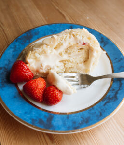 slice of Norwegian budapest cake on a blue plate with strawberries