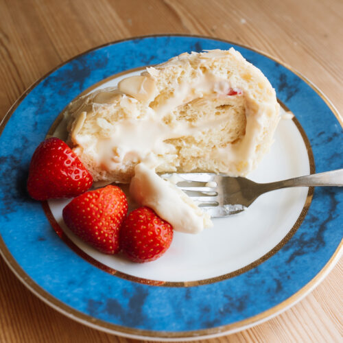 slice of Norwegian budapest cake on a blue plate with strawberries