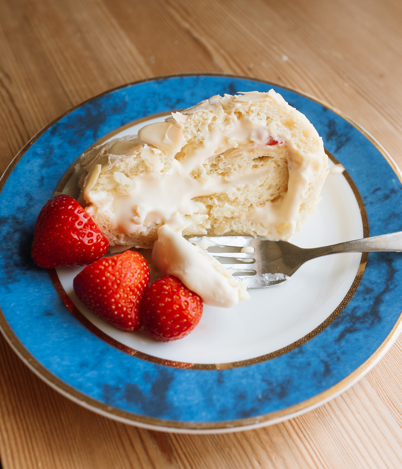slice of Norwegian budapest cake on a blue plate with strawberries