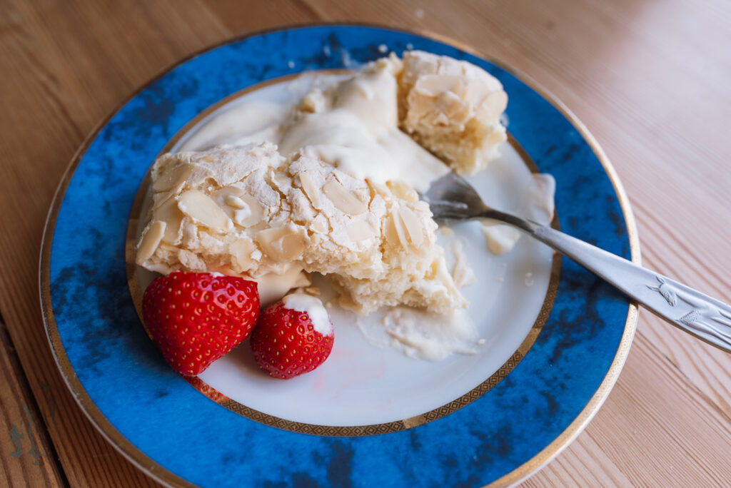 slice of Norwegian budapest cake on a blue plate with strawberries